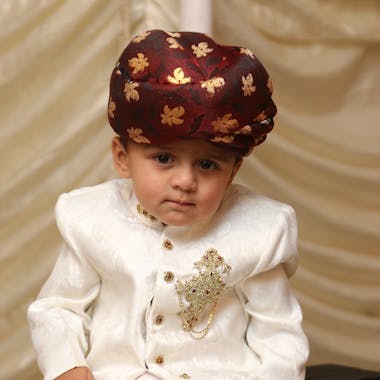Cute boy in traditional attire and headwear, highlighting cultural heritage.