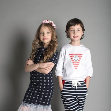 Two children posing in stylish nautical-themed outfits.
